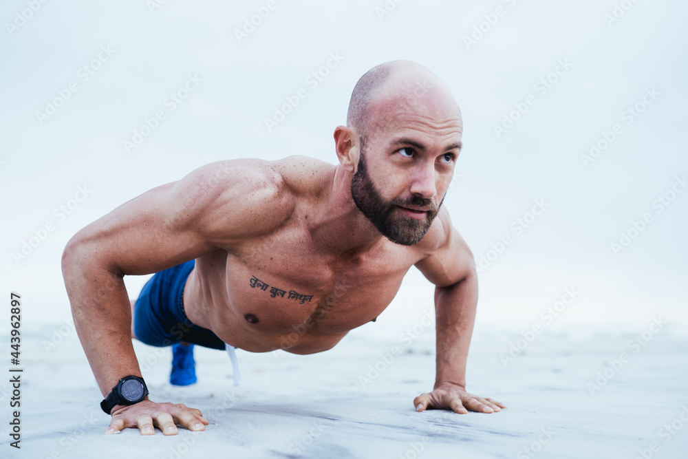Obraz premium Fitness Model doing Push up on beach from front