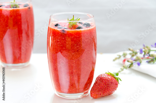 Two glasses of fresh berries fruit and smoothies on white . Blueberries and strawberries.
