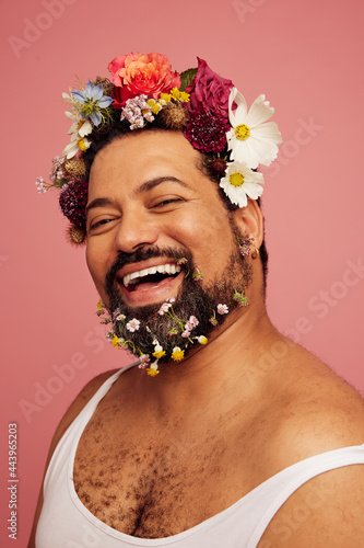 Cheerful male with flowers in hair and beard photo