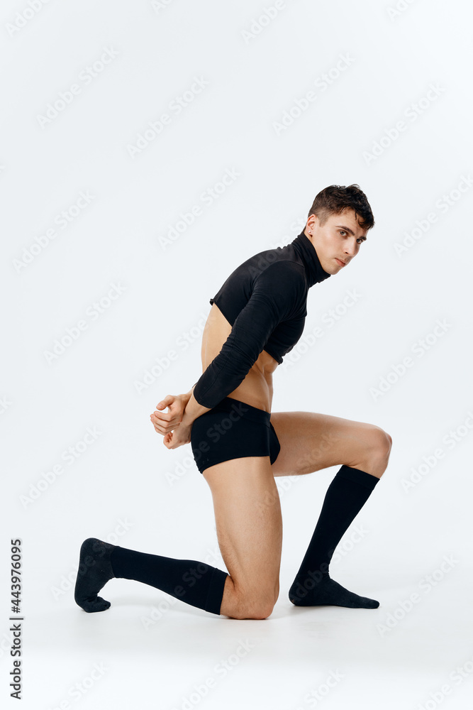 a man with an athletic physique stands on his knee in a sweater underpants and socks on a light background side view a man with an athletic physique stands on his knee in a sweater underpants and socks on a light background side view