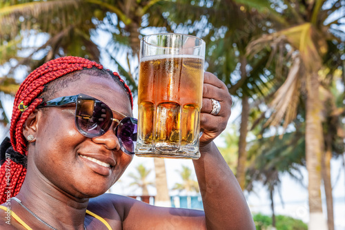 African happy woman drinking a beer out at a beach bar in Accra Ghana West Africa