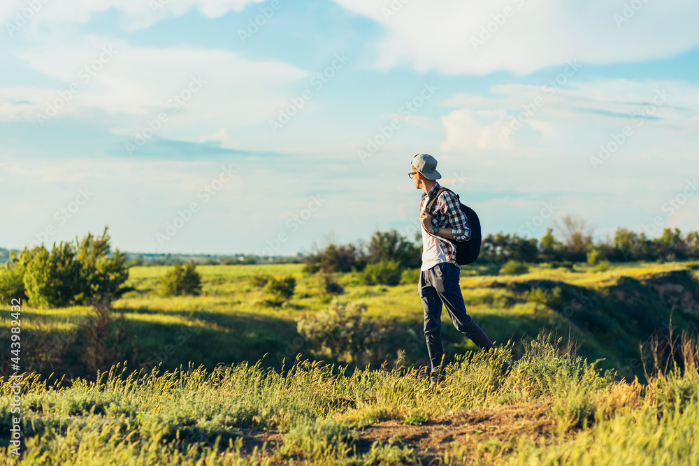 young man, with a backpack, walking and enjoying the view from the top on a bright sunny day young man, with a backpack, walking and enjoying the view from the top on a bright sunny day