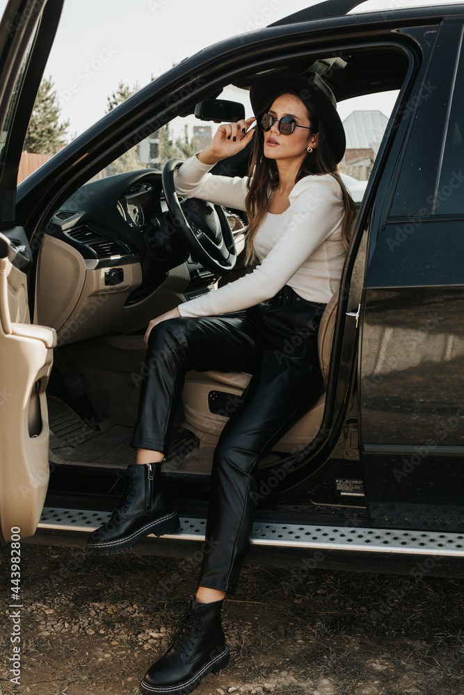 Portrait of a beautiful young woman driving a car. Lady in blackout glasses posing in the car Portrait of a beautiful young woman driving a car. Lady in blackout glasses posing in the car