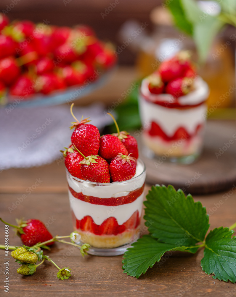 Strawberry dessert in a glass with a decor of cut strawberries standing on a wooden background Strawberry dessert in a glass with a decor of cut strawberries standing on a wooden background