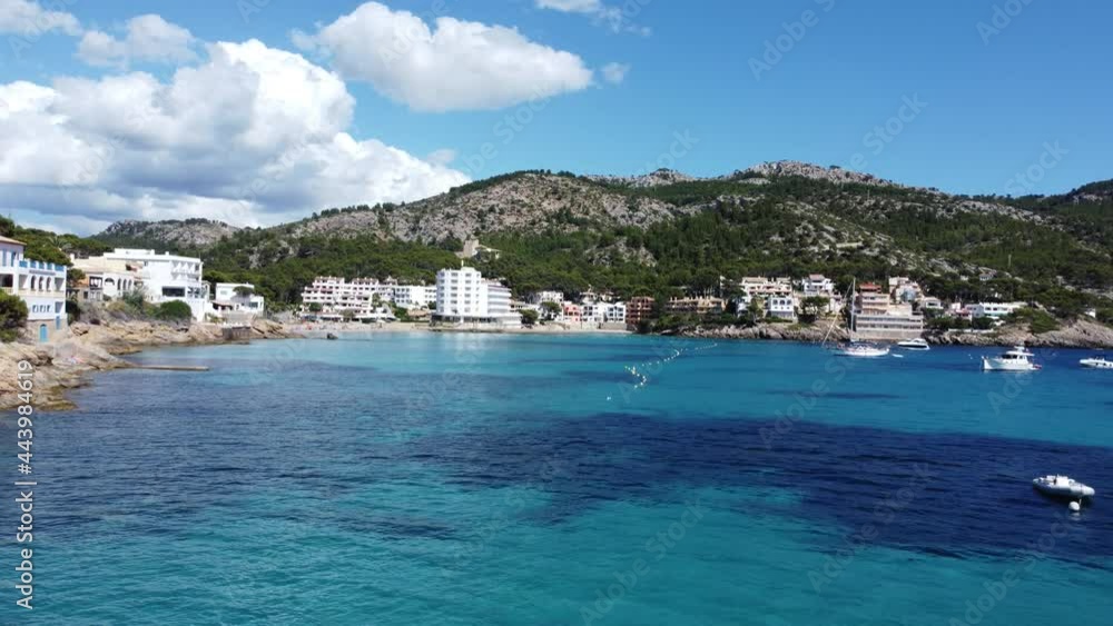 Steady drone shot over the shallow waters of a beautiful Mallorca Spain Cove with view on Mountains and Hills beaches and hotels on a summer day Steady drone shot over the shallow waters of a beautiful Mallorca Spain Cove with view on Mountains and Hills beaches and hotels on a summer day