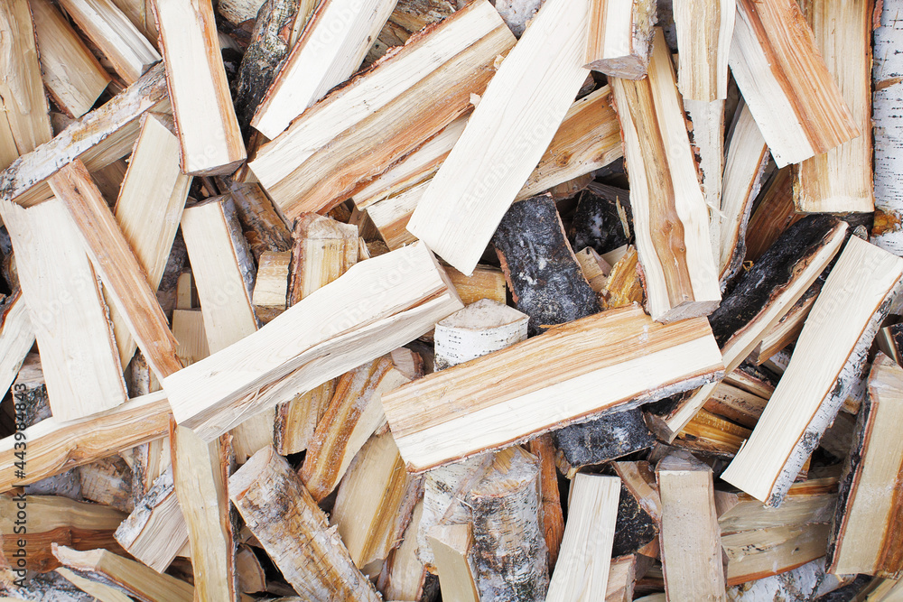 Lots of frozen, chopped birch logs. The firewood is sawn and split. The logs lie chaotically and piled up in a heap. A dark core is visible on the split wood. A texture or background. Lots of frozen, chopped birch logs. The firewood is sawn and split. The logs lie chaotically and piled up in a heap. A dark core is visible on the split wood. A texture or background.