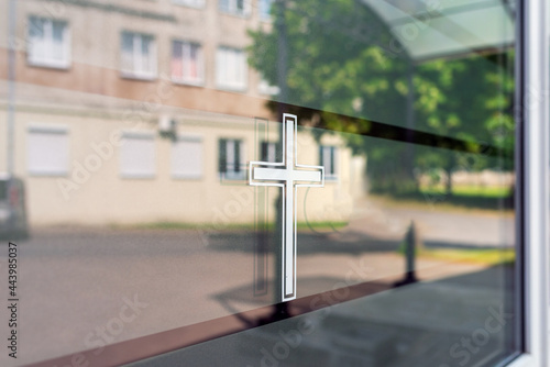 Closeup of a white cross on a window. Funeral house summer day after covid-19 pandemic.Copy space. © ARVD73