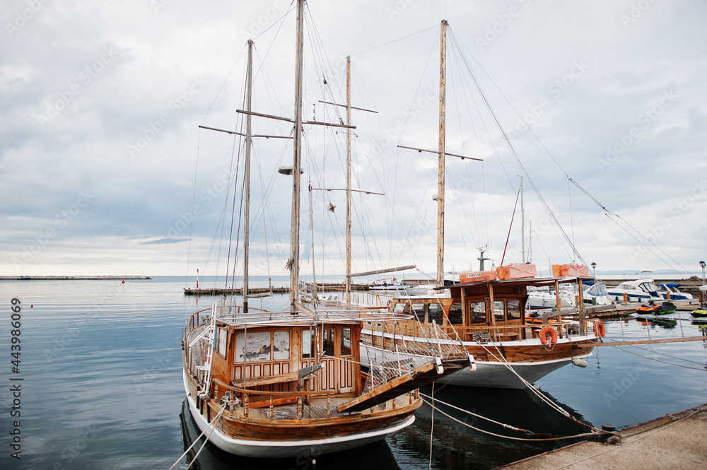 Two wooden old sailing ship stay on dock.