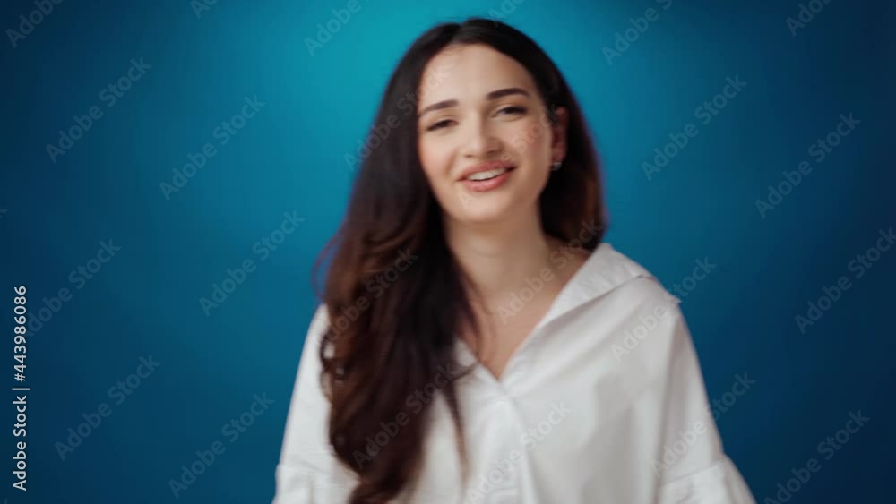 Cheerful young woman smiling and laughing against blue background Cheerful young woman smiling and laughing against blue background