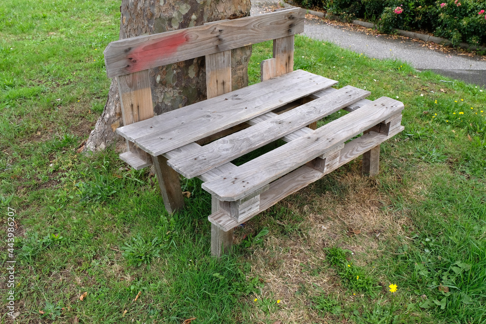 Banc fabriqué avec des palettes sur une pelouse au pied d'un arbre Banc fabriqué avec des palettes sur une pelouse au pied d'un arbre