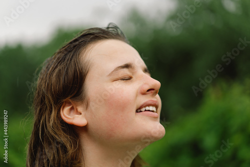 Close-Up Portrait Of Teenager Girl. Cheerful Teen Girl With Pronounced Face From Sprayed Small Splashes Of Water Or Warm Summer Rain In Outdoors.