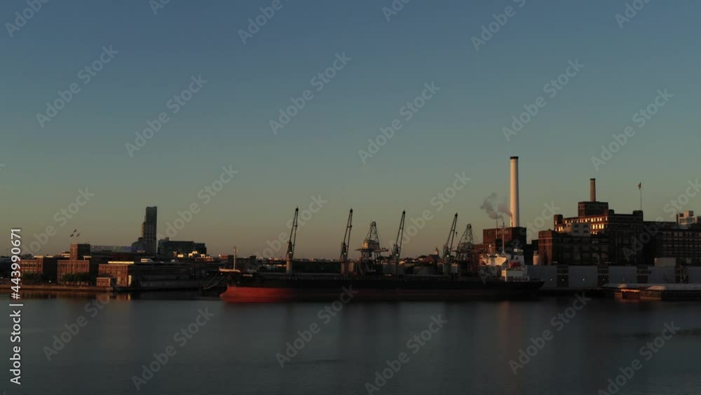 Aerial rise looking at industrial ship and factory across the Patapsco River in Baltimore Maryland at blue hour sunrise Aerial rise looking at industrial ship and factory across the Patapsco River in Baltimore Maryland at blue hour sunrise