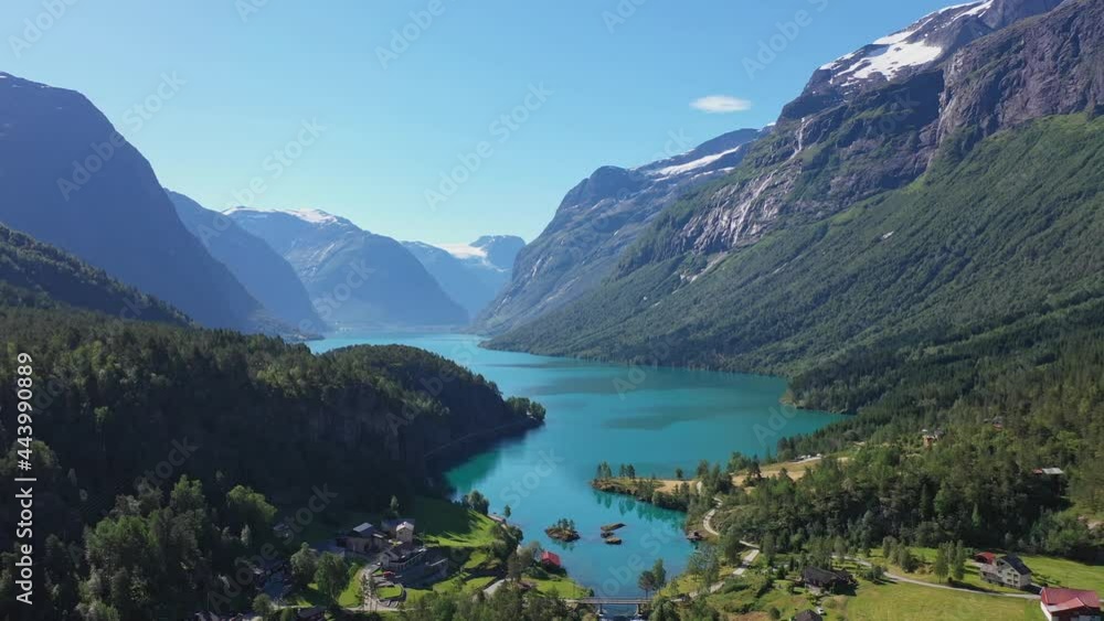 Spectacular view of Loen turquoise glacier water among epic mountain scenery with deep valley and snow capped mountains - Reverse aerial Loen Nordfjord Norway