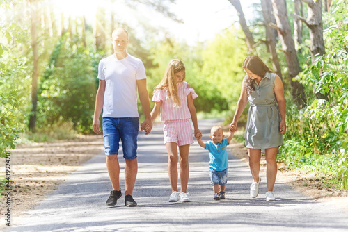 Family with two children walking in summer park together