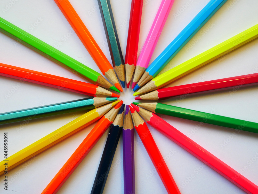 Colored pencils on a white background radiate rays to the sides. They are closed with a rod in the center. Colored pencils on a white background radiate rays to the sides. They are closed with a rod in the center.