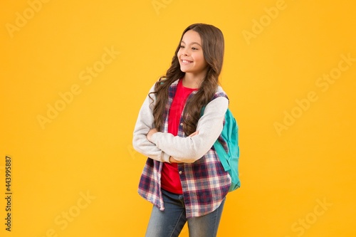 Confident back to school child happy smile keeping arms crossed yellow background, confidence
