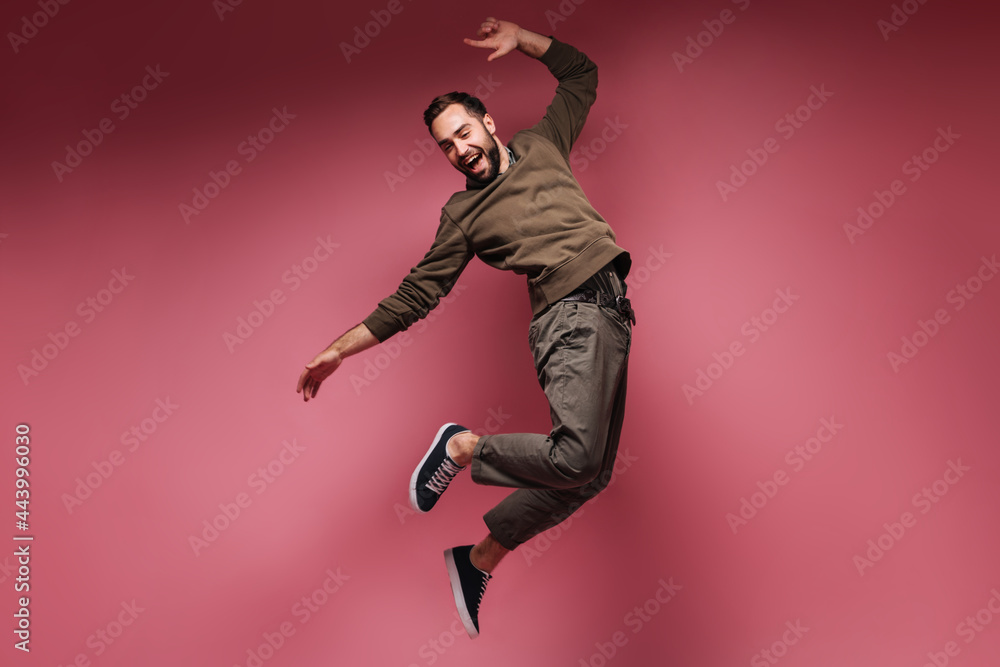 Man has fun and jumps on pink background