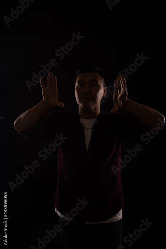 Asian man dances to music in the dark on a black background © dmitriisimakov