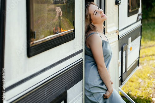 The girl stands near the trailer and looks away enjoying the moment and smiles