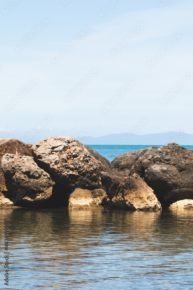 Sea and rock background. Rock and blue sea with clear sky. Seaside travel destination background image. Clear blue sea and blue sky in summertime