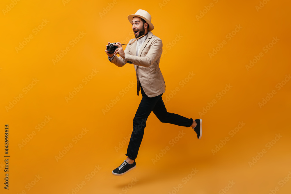 Happy man in stylish outfit jumping and taking photos Happy man in stylish outfit jumping and taking photos