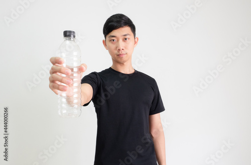 Young Asian man black shirt holding plastic bottle in hand with confident face on white isolated background