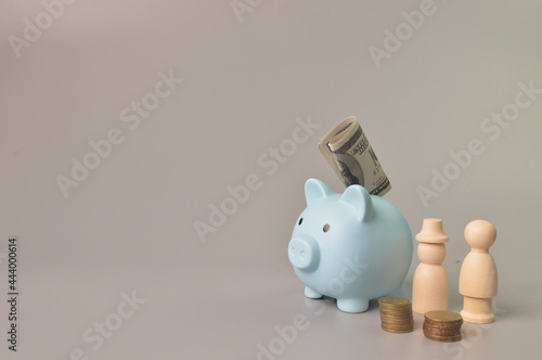 People figures, piggy bank, coins and money banknotes. Copy space