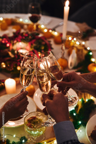 Cheers with champagne. People clink glasses of champagne at the holiday table on New Year's Eve. High quality photo