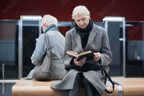 two women waiting for a train sitting on a bench in the subway.