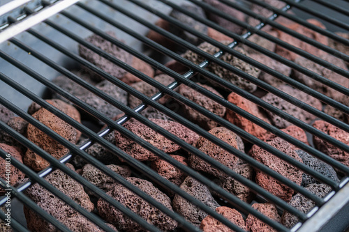 Fragment of a barbecue grill and lava stones. Selective focus. Space for lettering and design