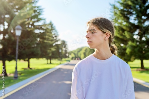 Portrait of handsome teenage guy, profile view outdoors, copy space