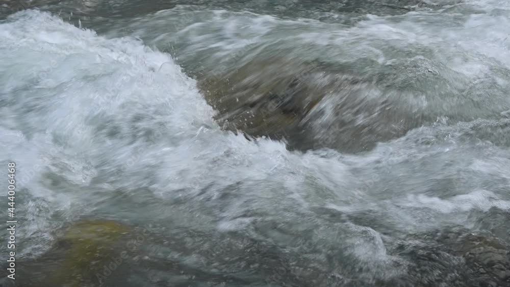 Slow motion of wild clear mountain river , stream flowing through rocks. Close up of river stones with flowing water, clean water flowing in a mountain river Slow motion of wild clear mountain river , stream flowing through rocks. Close up of river stones with flowing water, clean water flowing in a mountain river