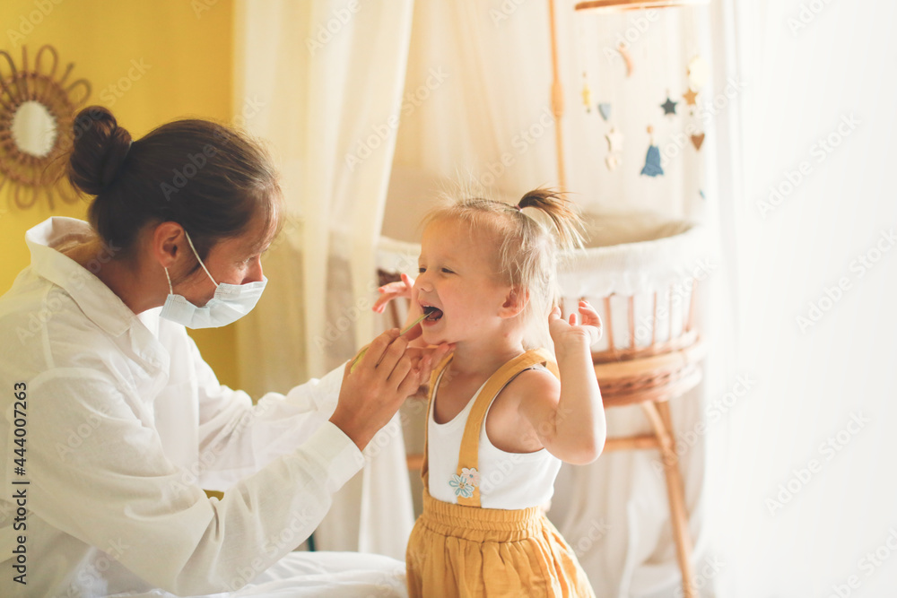 funny little girl Toddler shows her throat to nurse in mask and white coat, calling doctor at home, patronage. Examination of pediatrician in a real interior,concept of medicine and disease prevention funny little girl Toddler shows her throat to nurse in mask and white coat, calling doctor at home, patronage. Examination of pediatrician in a real interior,concept of medicine and disease prevention