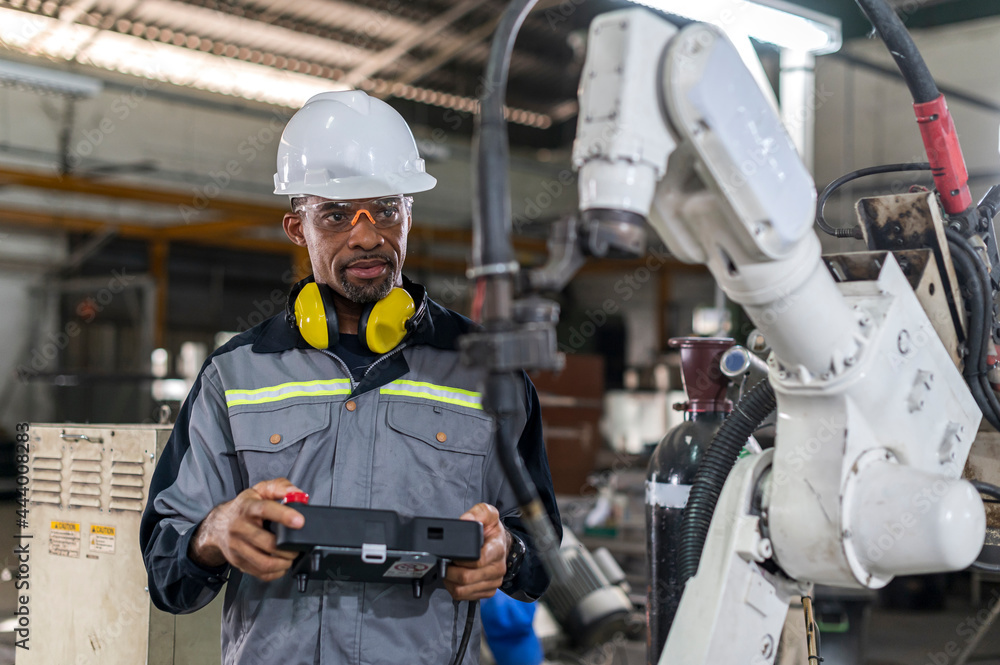 Robotics control engineers setting and maintain spare parts of industrial robot arm controller in production plant factory