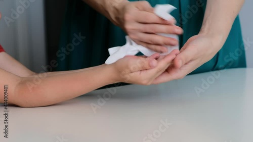 Woman using wet antiseptic wipe to clean child's hands, protect from virus, pandemia, covid. Close up