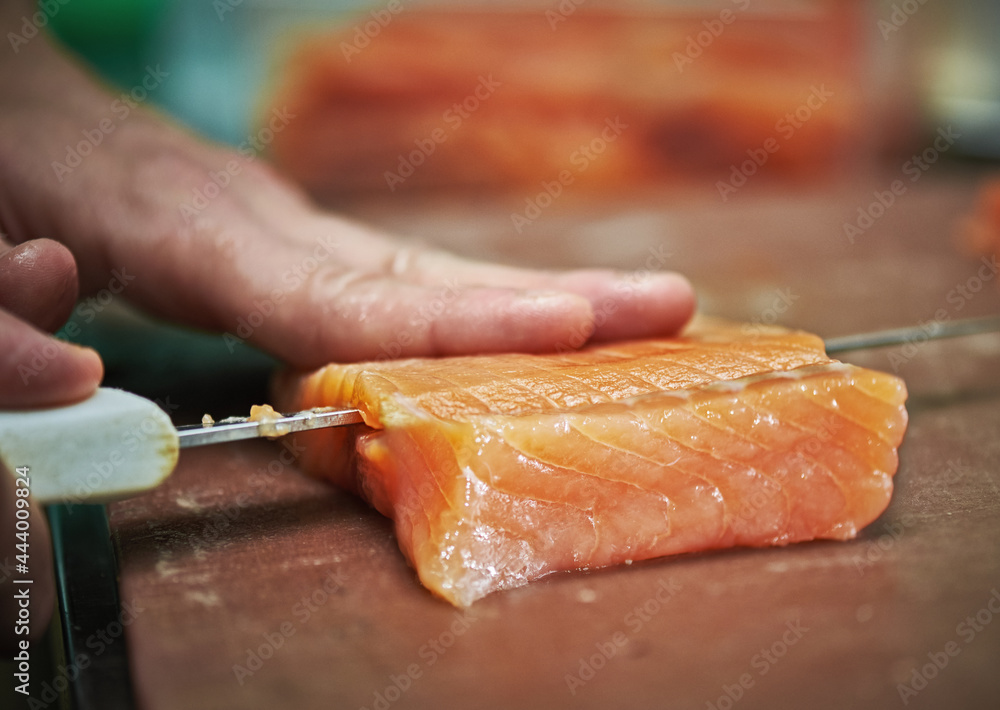 chef slicing salmon, making sushi in restaurant