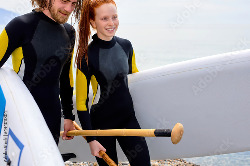 Sportive couple go to ocean. Woman and man holding surfboard on beach. Surfers ready to surf on the beach together. Outdoor Active Lifestyle. It's time for surfing . Copy space