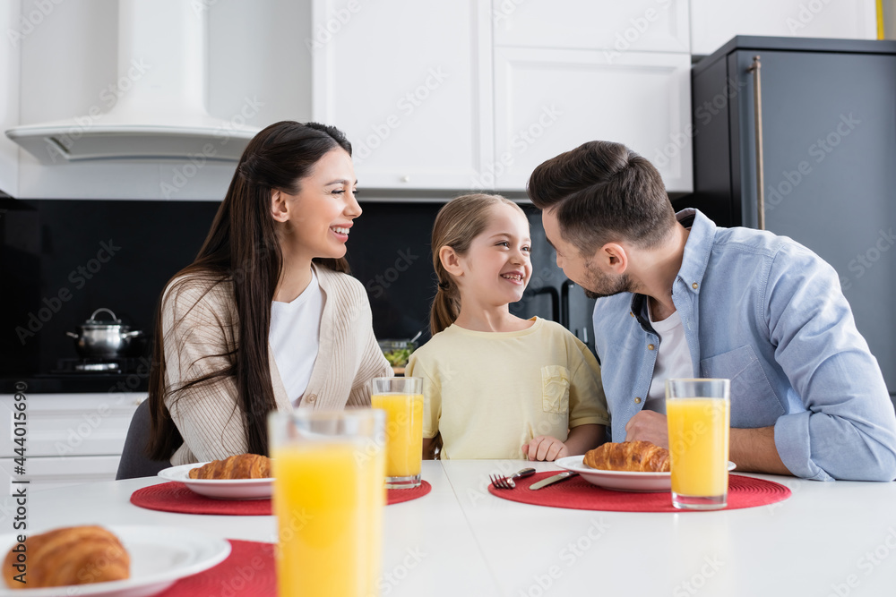 man looking at cheerful daughter near wife smiling during breakfast