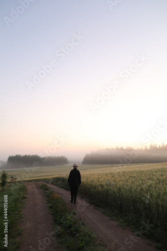 silhouette of a man walking in a scenic countryside landscape at sunrise