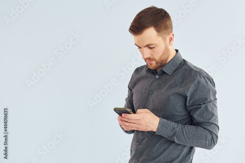 Man in grey shirt is posing indoors against white background