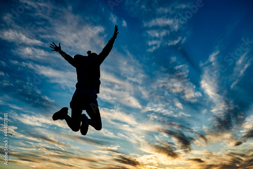 Happy woman having fun jumping with sky dawn on background - Focus on female silhouette