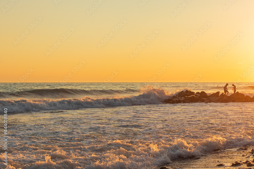 Fototapeta premium Dark blue waves against the beautiful orange sunset at the Black Sea, Anapa, Russia