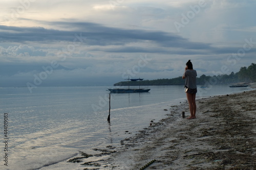 Touristin schaut sich Sonnenuntergang an am Meer in Asien am Strand