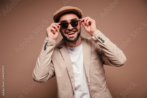 Man in cap laughs and takes off his sunglasses photo