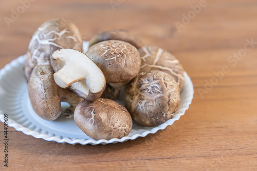 Group Shiitake mushrooms on dish on wooden background.