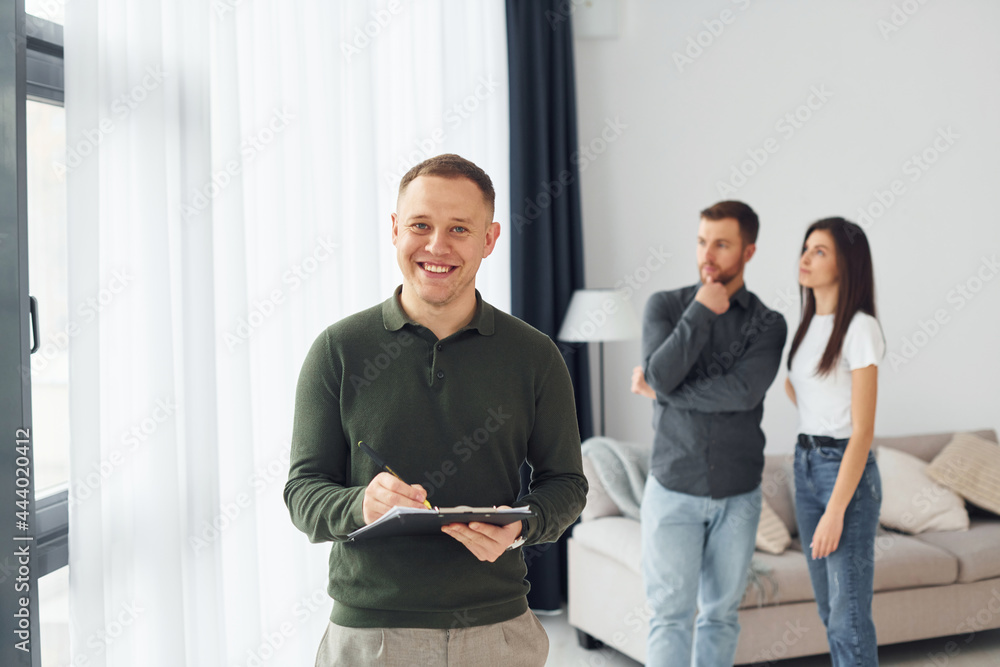 Salesman helps young couple in choosing an apartment. Conception of business and rent Salesman helps young couple in choosing an apartment. Conception of business and rent