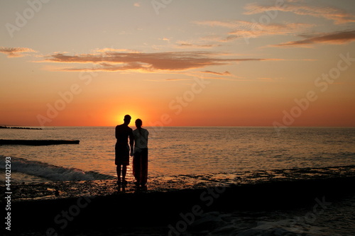 dark silhouettes of young people on the background of the sunset on the sea