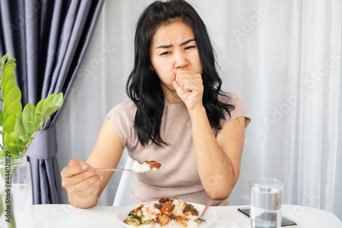 Asian woman choking while eating a meal she has food stuck in the throat and try to vomit or cough photo