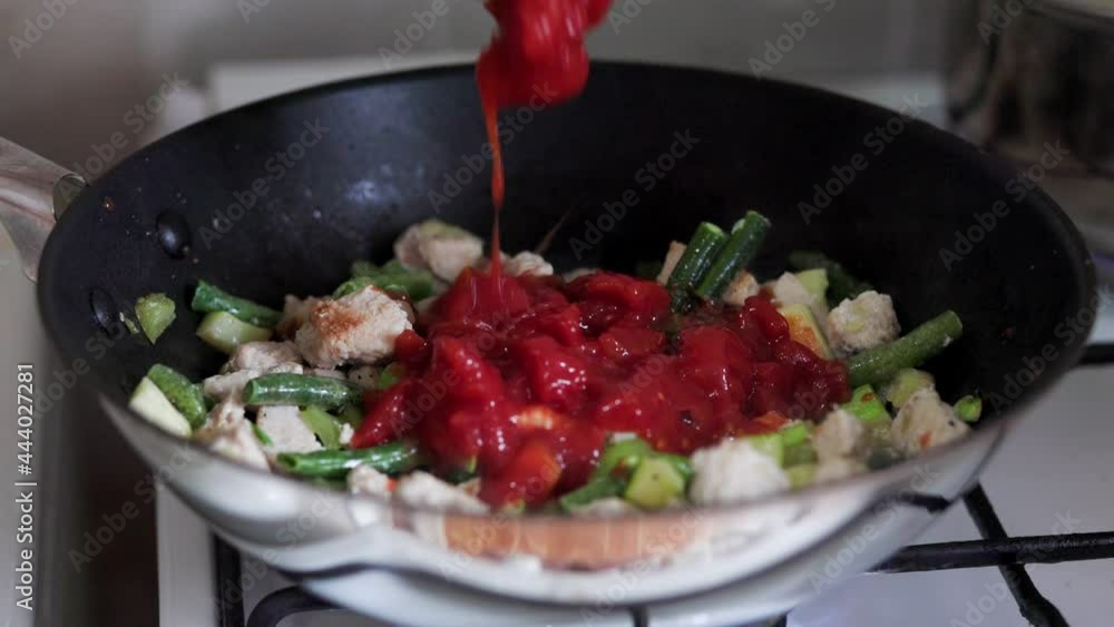 A woman cooks Thai food at home in a wok. Adds tomatoes and mixes. Real time. Close up. A woman cooks Thai food at home in a wok. Adds tomatoes and mixes. Real time. Close up.