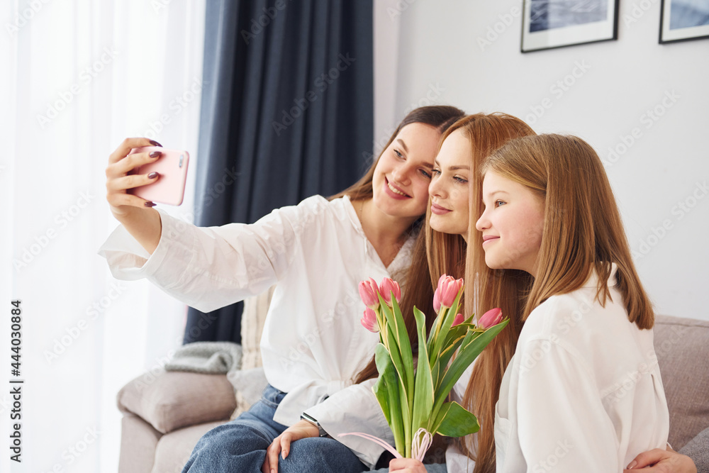 Making selfie. Young mother with her two daughters at home at daytime